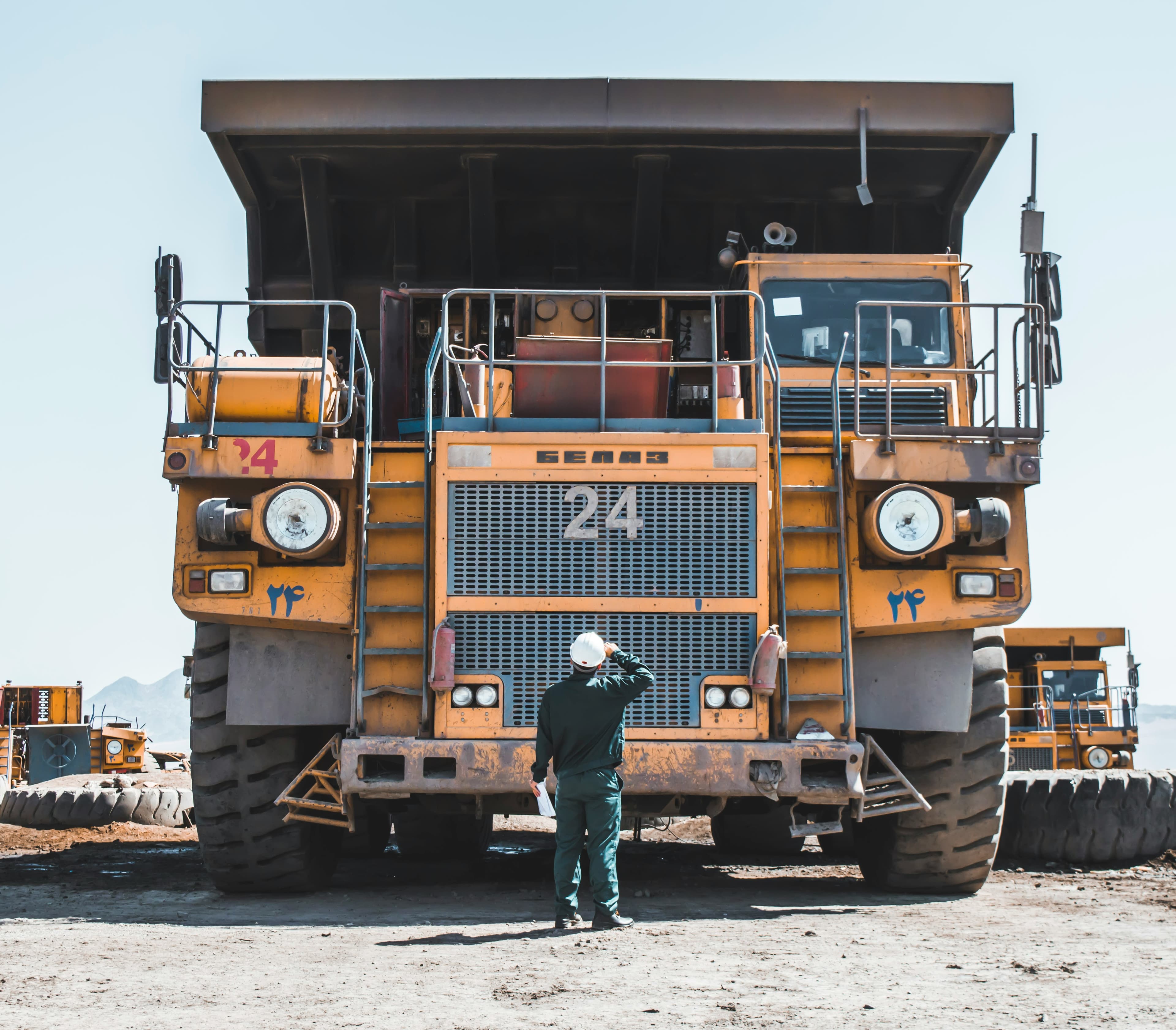 Technician inspecting a large yellow haul truck on a construction site